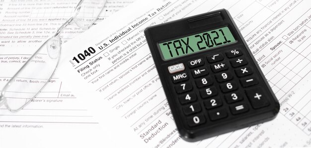 Tax forms 1040, calculator with sign TAX 2021 and pen on the table