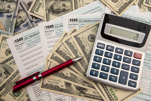 Фото Налоговые формы 1040 с долларами и калькулятором для заполнения за апрель. понятие налогов.