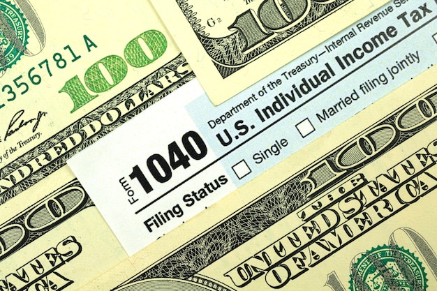 Tax forms among hundred dollar bills close-up, concept of tax season, time to pay