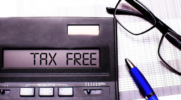 TAX FREE is written in the calculator near black-framed glasses and a blue pen.