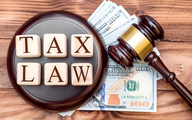 Tax law concept Words TAX LAW with judge's gavel and money on the table Top view