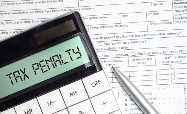 Tax penalty words on calculator display with tax forms