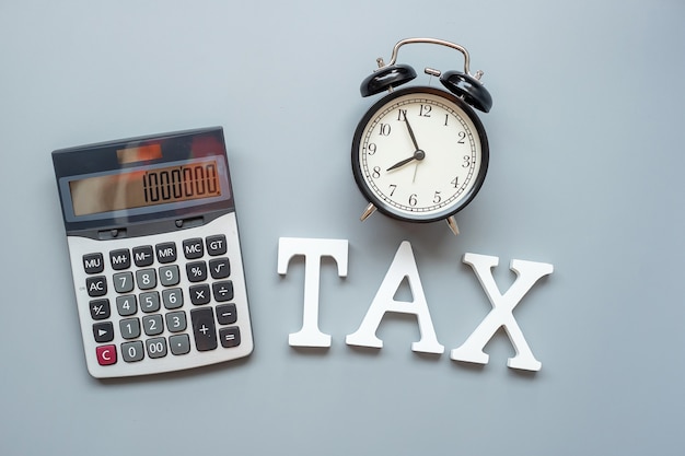 TAX text with calculator and alarm clock . investment and time to tax concepts