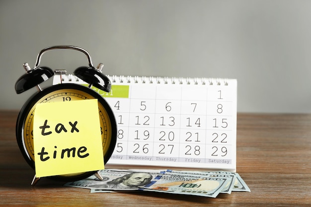 Tax time on alarm clock with dollars and calendar