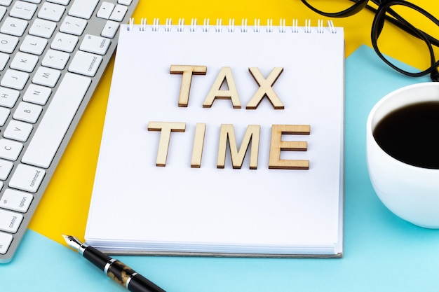 Tax Time houten letters met belastingformulier en kopje koffie.