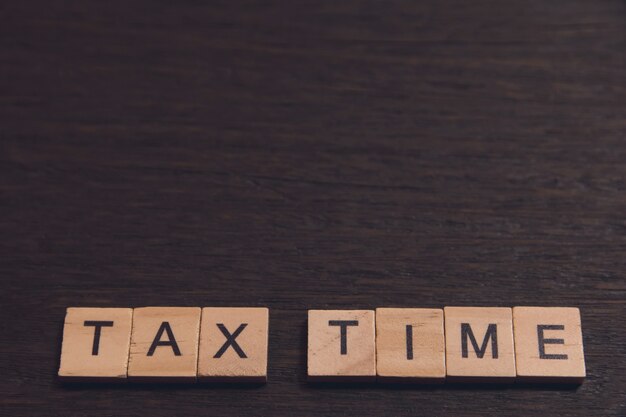 Tax time with wooden alphabet blocks on dark plank wooden with copy space