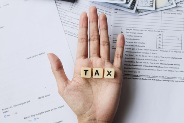 TAX words on palm hands against the tax forms