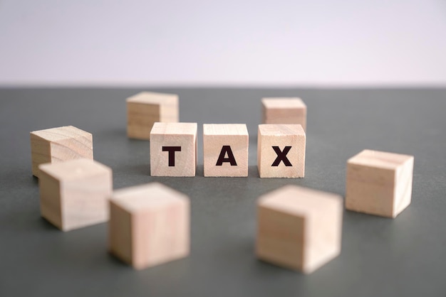 TAX written on wooden blocks on dark grey background