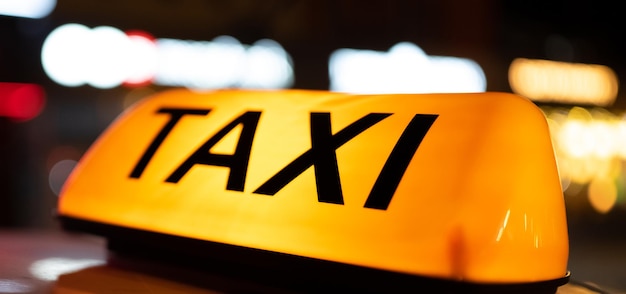 夜の街の暗い通りのタクシー車のライトがクローズアップされ、車の屋根にあるタクシーの看板が点灯します。