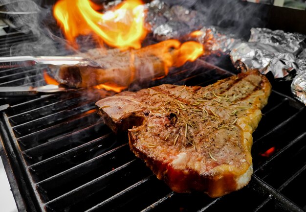 Tbone steak grilled on a hot and smoky oven sprinkled with pepper and salt and dried rosemary