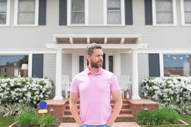 Te koop. knappe makelaar die op bezoekers wacht. nieuwe woning huren. eigendom. zelfverzekerde man buiten het nieuwe Amerikaanse huis. succesvolle makelaar die een huis koopt voor investeringsdoeleinden.