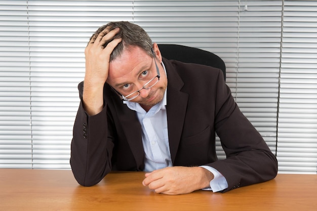 Te veel werk. Portret van uitgeputte zakenman die aan een bureau zit