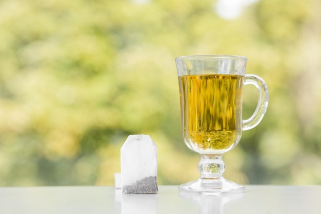 Tea bag and cup of tea on green summer background