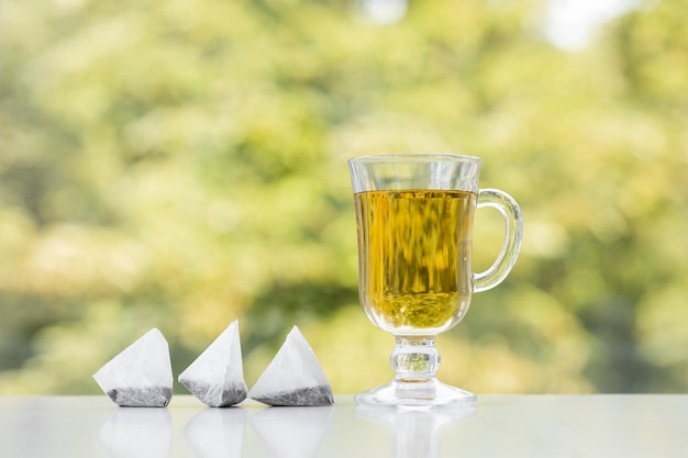 Tea bag and cup of tea on green summer background