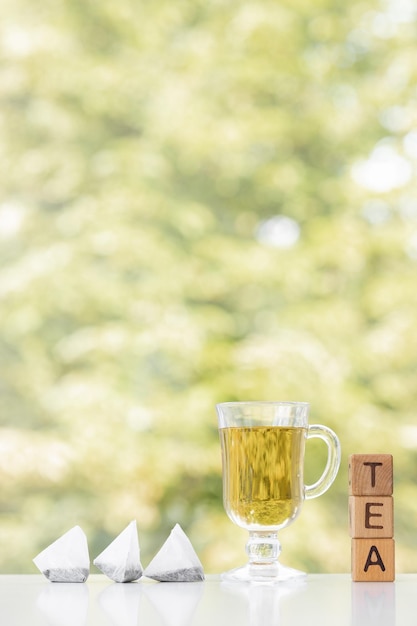 緑の夏の背景にティーバッグとお茶のカップ