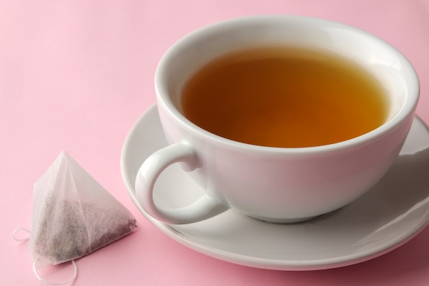 Tea bag pyramid and cup with tea on a delicate pink background. to make tea.