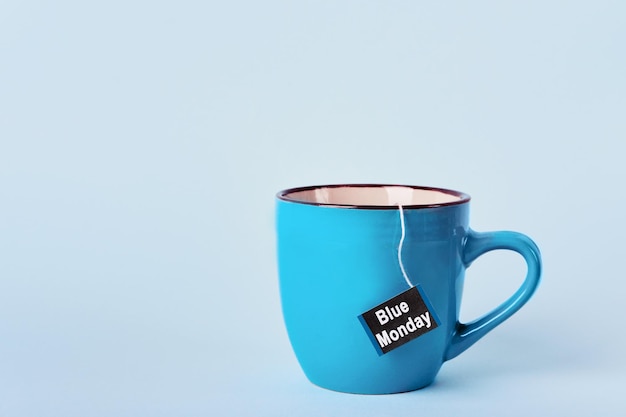 Photo tea bag with blue monday text in blue mug on blue background most depressed day of the year concept