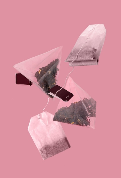 Foto le bustine di tè volano su uno sfondo rosa