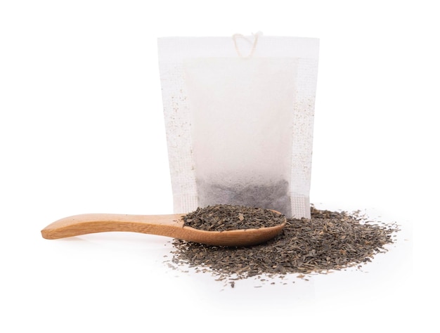 Tea bags and spoon with dry leaves on white background