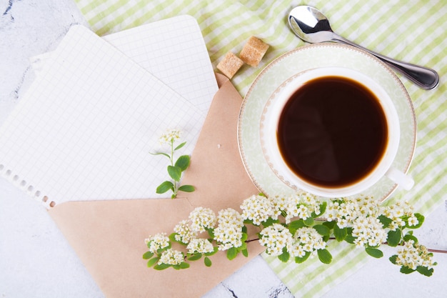 美しい白いカップのお茶。紙のシートとクラフトメールの封筒。朝ごはん。開花スピレアの枝。日本のコンセプトわびさび