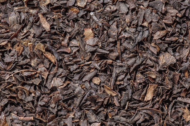 Tea black small chopped dried leaves brown background uniform texture in bulk closeup macro top view