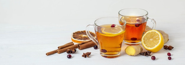 Tea to boost immunity. Warming medicinal tea with lemon, ginger, cinnamon and cranberries. A banner on a white background. High quality photo