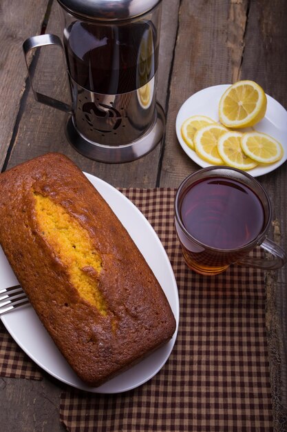 Tea, cake and lemons lying on an obsolete wooden table