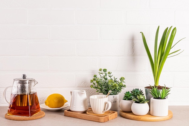 Foto oggetti della cerimonia del tè disposti su bancone in pietra della cucina con piante in vaso parete in mattoni bianchi spazio di copia sfondo della cucina