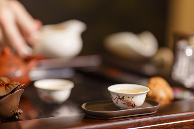 Photo tea ceremony. master pours tea on white cups.