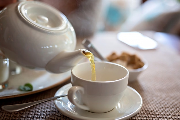 Tea ceremony of pouring tea into a porcelain white Cup