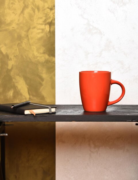 Tea or coffee cup with copybook and pen