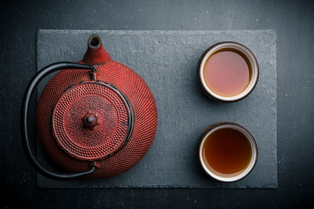 Чайная композиция с керамическими чайными чашками и красным железным чайником