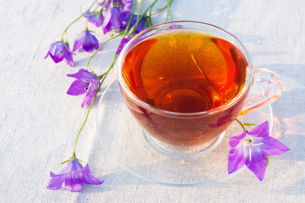 Tea cup and blue bell flowers on linen napkin