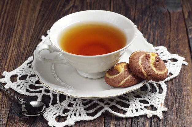 Tea cup and cookies with chocolate on dark wooden table