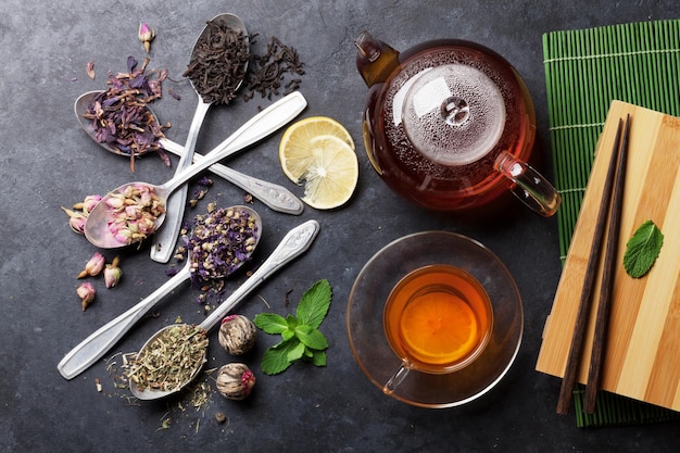 Tea cup teapot and assortment of dry tea in spoons