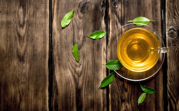 Tea Cup with leaves. On wooden table.