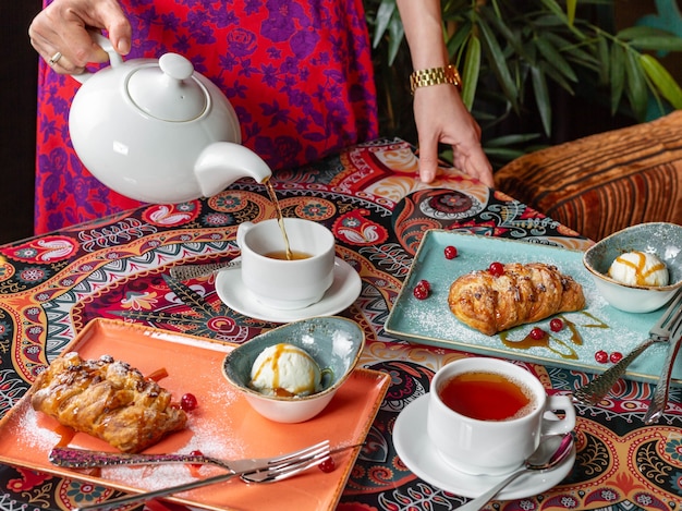 写真 お茶を飲みながら、新鮮な食欲をそそるシュトルーデルのある美しいテーブルにお茶を注ぎます。側面図