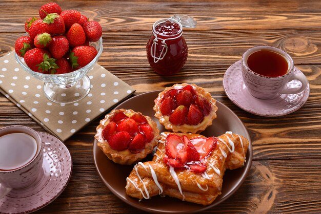 Tea drinking with tartlets and cakes with strawberries