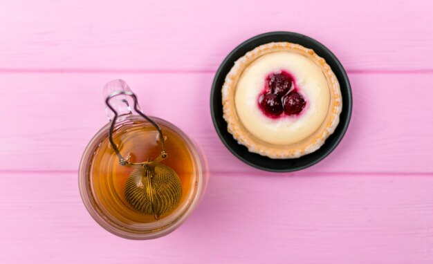 ガラスのお茶とピンクの木製の背景にケーキ