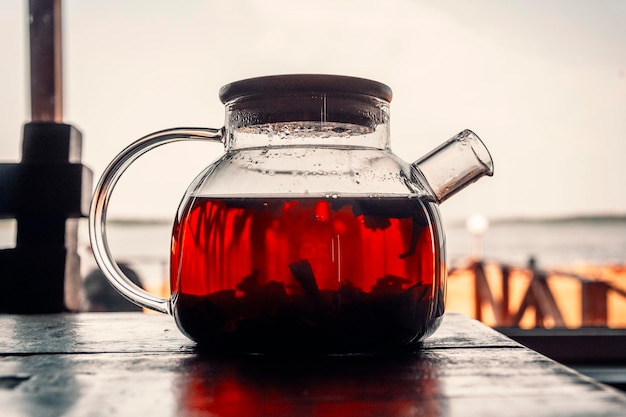 Tea in a glass teapot on a wooden table in the open air Coastal cafe brunch