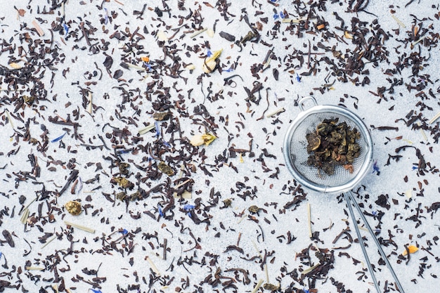 Tea leaves for brewing in a strainer on a gray background. Copy space.