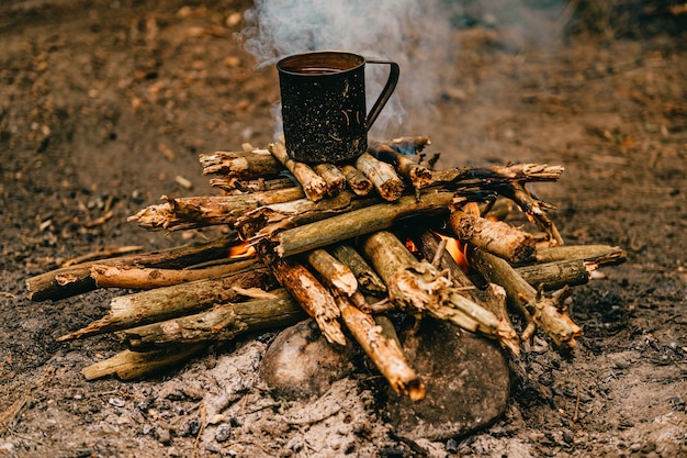 Tea in metal mug heats up on bonfire