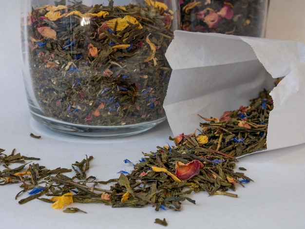 Tea mixture of herbs in a glass jar The tea leaves are scattered on the table