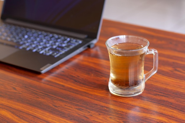 Tazza da tè con messa a fuoco selettiva e laptop sul tavolo soffiato. foto orizzontale.