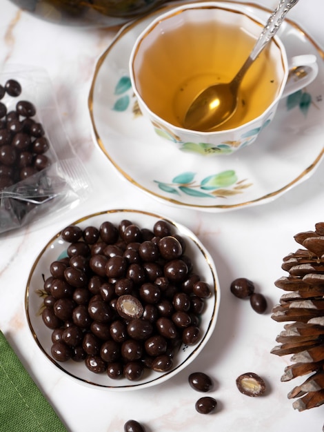 Tea party with healthy sweets A mug of tea and a plate of Pine nuts nuts in chocolate glaze Almost top view