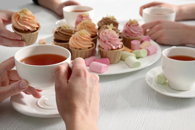 Tea Party with sweet creamy cakes over wooden table background