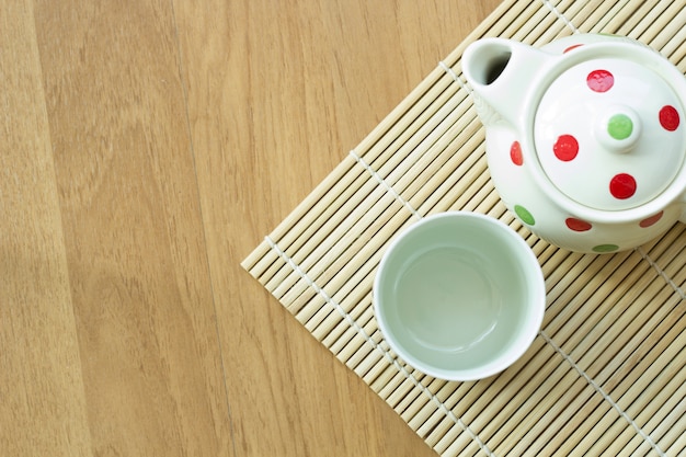 Tea pot and cup on wooden table.