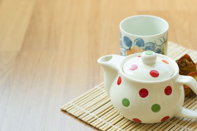 Tea pot and cup on wooden table.