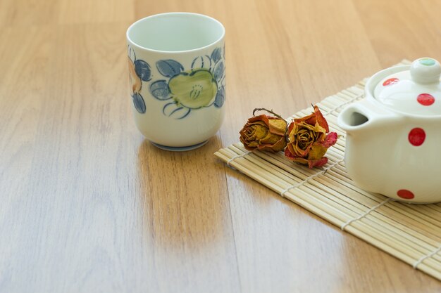 Tea pot and cup on wooden table.