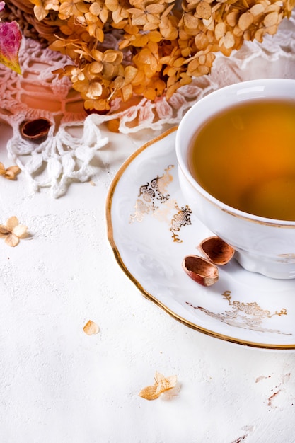 Foto tè in stile rustico vintage chic. festa del tè in giardino. teiera di fiori secchi. tazza di tè con decorazioni autunnali sul tavolo, con ortensie e zucca